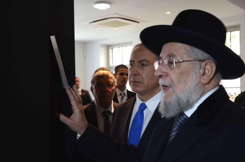 Rabbi Lau, Chairman of the Yad Vashem Council, affixing a mezuzah at the entrance to the exhibition 
